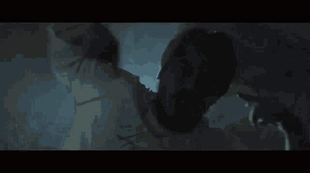 a person is standing in a dark room with a light coming through the window .