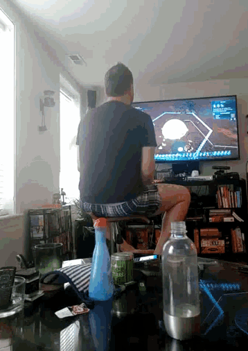 a man sits on a bar stool watching a baseball game on the television