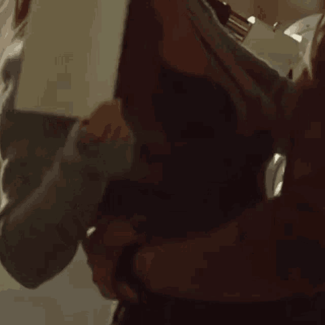 a close up of a person holding a baby in a sling in a dark room .