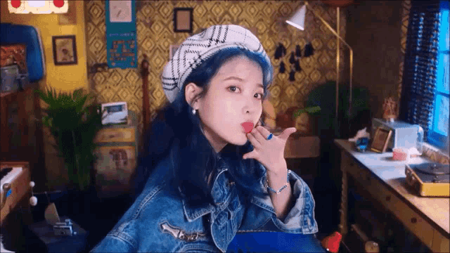 a woman with blue hair wearing a beret and a denim jacket