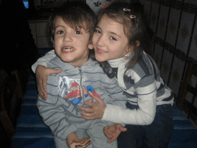 a boy and girl are posing for a picture and the boy has a spiderman shirt on