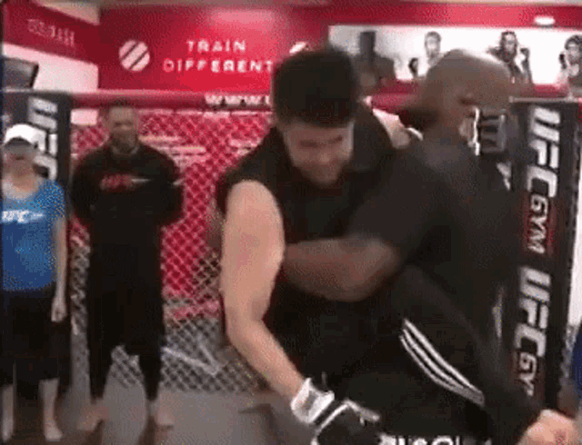a man in a ufc gym is being lifted by another man