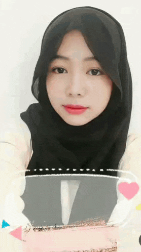 a woman wearing a black hijab and a white shirt .