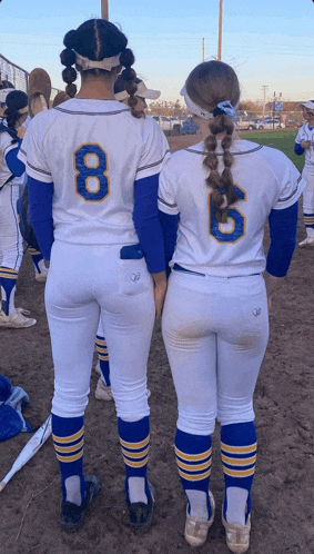 two softball players standing next to each other with one wearing the number 8