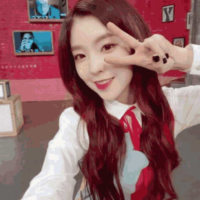 a woman with red hair is making a peace sign