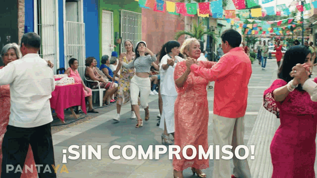 a group of people are dancing on a street with sin compromiso written on the bottom right