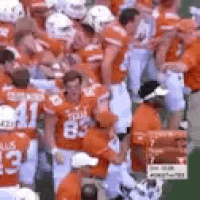 a group of football players are standing in a stadium during a game .
