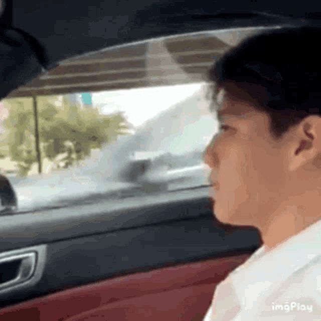 a man is driving a car and looking out the window .