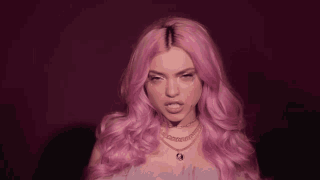a woman with pink hair is wearing a necklace