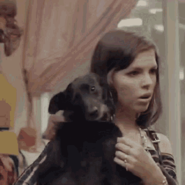 a woman is holding a black dog in her arms in a room .