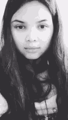 a black and white photo of a young woman with long hair looking at the camera .