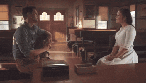 a man and a woman are sitting at a table and talking