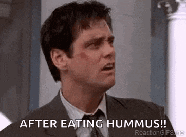 a man in a suit and tie is eating hummus .
