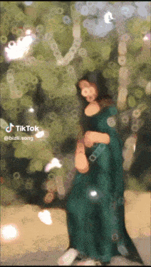 a woman in a green dress stands in front of a tree with a tiktok sticker