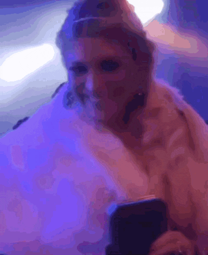 a woman in a fur coat is eating cotton candy while holding a cell phone