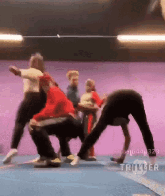 a group of people are doing a handstand on a blue mat with triller written in the corner