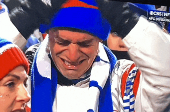 a man wearing a blue hat and scarf is crying in front of a cbs live advertisement