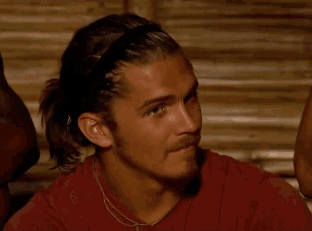 a man wearing a headband and a red shirt looks at something