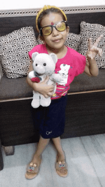 a little girl wearing sunglasses holds a teddy bear in her hands