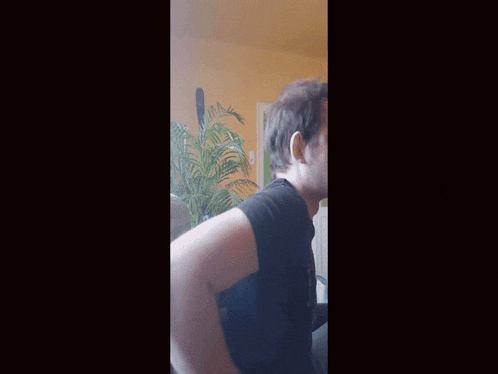 a man in a black shirt is sitting in a chair in a living room