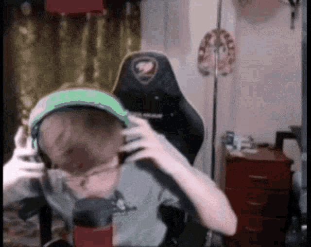 a person is wearing headphones and a hat while sitting in a chair .