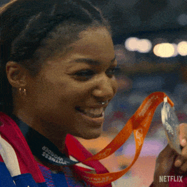 a close up of a woman holding a medal with a netflix logo in the corner