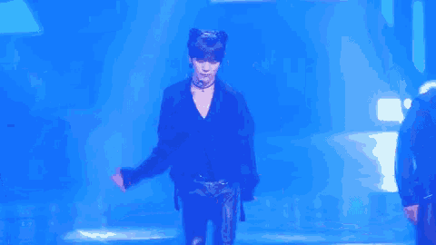 a man is dancing on a stage in front of a blue background with the words `` good boy '' written on it .