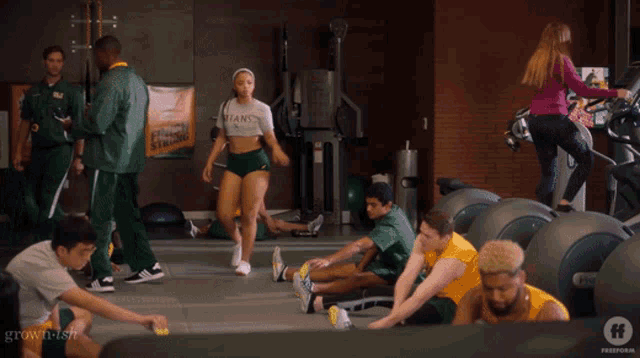 a woman in a titans shirt stands in a gym surrounded by people
