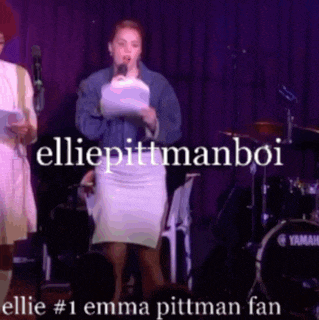 a woman speaking into a microphone on a stage with the words ellie pittman boi above her