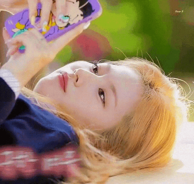 a woman is laying down looking at a cell phone .