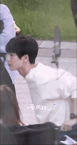 a young man in a white shirt is walking down a street