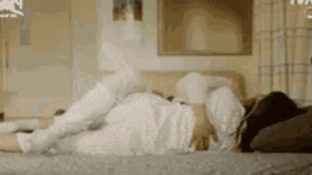 a woman is laying on her stomach on a bed in a living room .
