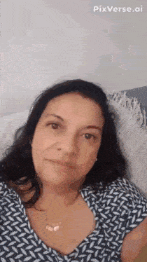 a woman is sitting on a couch wearing a necklace and a blue shirt .