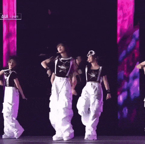 a group of women are dancing on a stage with a sign that says ' a ' on it