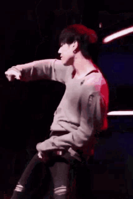 a man with a tattoo on his arm is dancing on a stage in front of a green light .