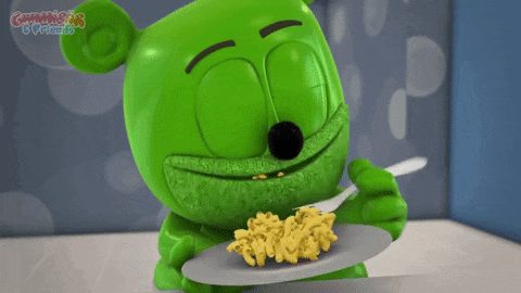 a gummy bear is eating macaroni and cheese with a fork from a plate