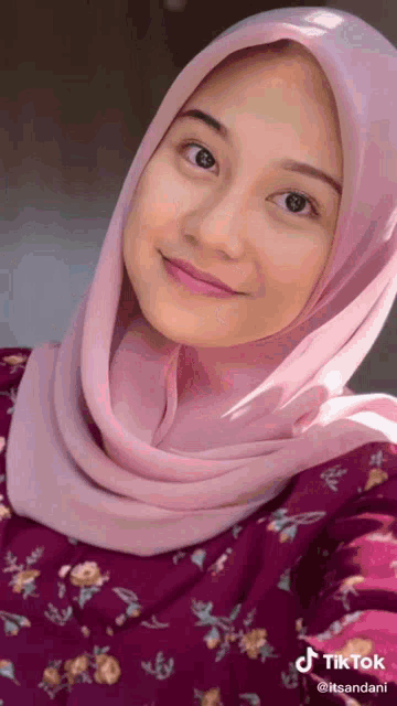 a woman wearing a pink hijab and a purple dress