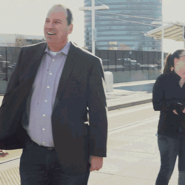 a man in a suit and a purple shirt is smiling