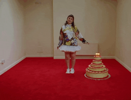 a woman in a tutu stands next to a cake with candles on it