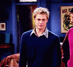 a man in a blue sweater is standing next to a woman in a pink sweater in a living room
