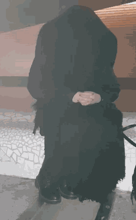 a person in a black hooded jacket sits on the ground