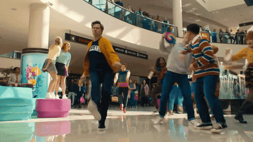 a group of people are dancing in a mall and one of them is wearing a shirt that says ' ucla '