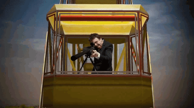 a man in a suit is holding a gun in a yellow ferris wheel