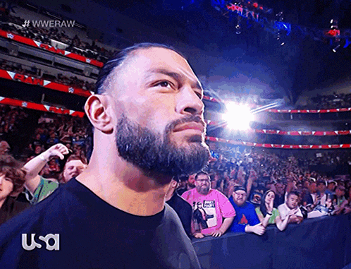 a man with a beard is standing in front of a crowd wearing a black shirt that says usa