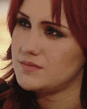 a close up of a woman 's face with red hair looking at the camera