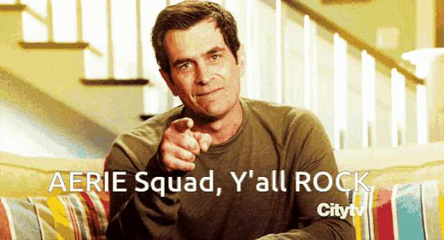 a man sitting on a couch pointing at the camera with the caption aerie squad