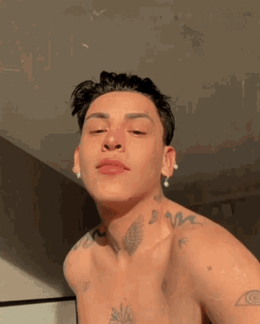 a shirtless young man with a lot of tattoos on his chest and neck