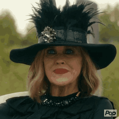 a woman wearing a black hat with feathers and a necklace is sitting in a chair .