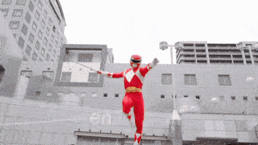 a red power ranger is jumping in the air in front of a building with the word en on it
