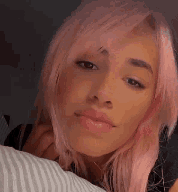 a woman with pink hair is laying on a striped pillow .